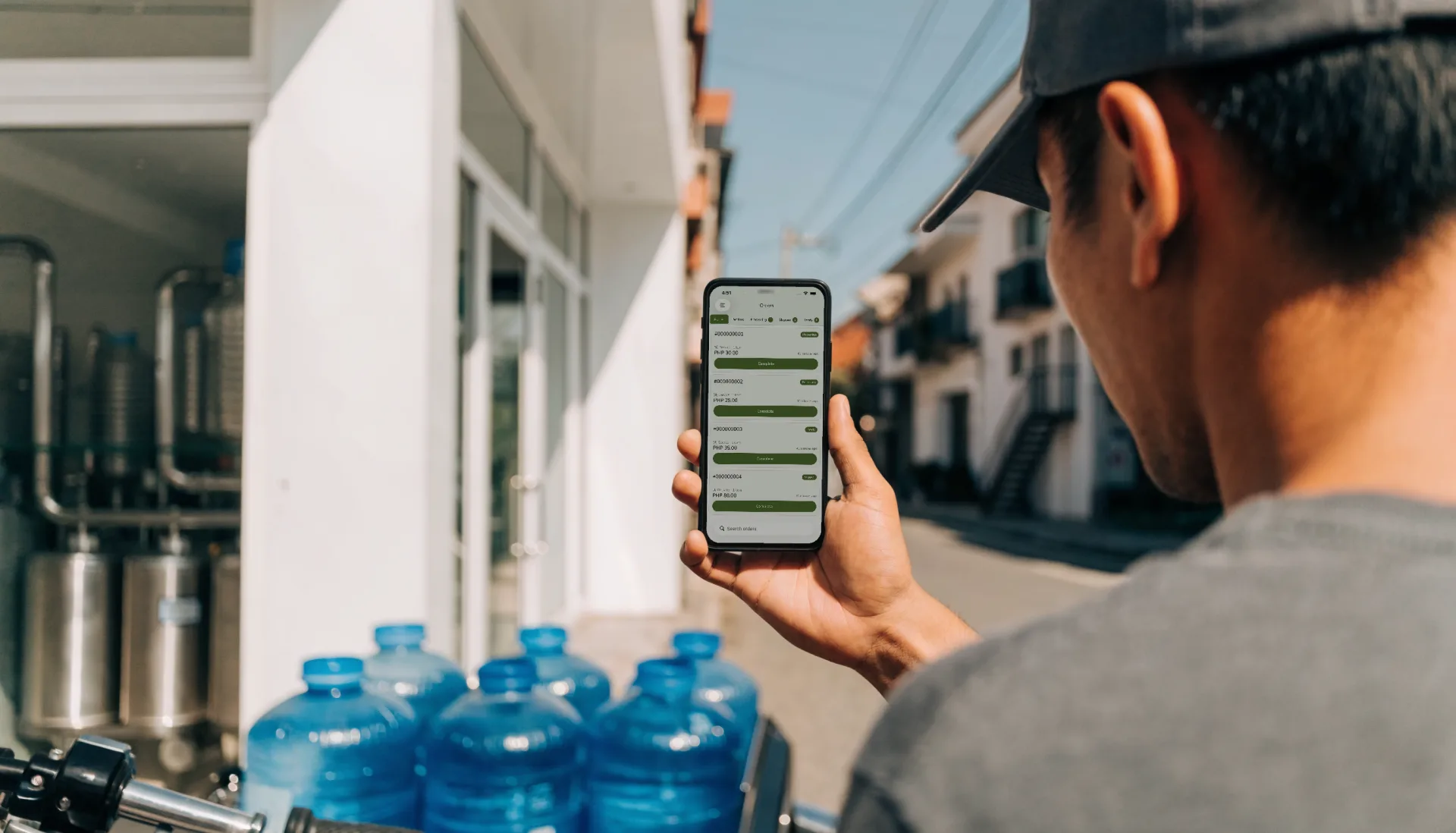 The rider beside his sidecar of water containers checks his orders, a delivery marked Shipped, on Fuze Store on his phone.
